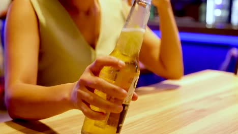 mujer sosteniendo una botella de cerveza fría en un restaurante