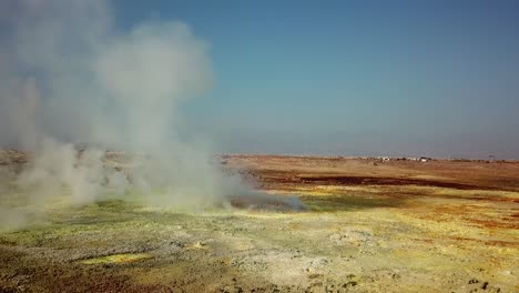 hot steam is going from hydrothermal field in danakil depression caused by tectonic plates in africa - aerial reveal of natural wonder