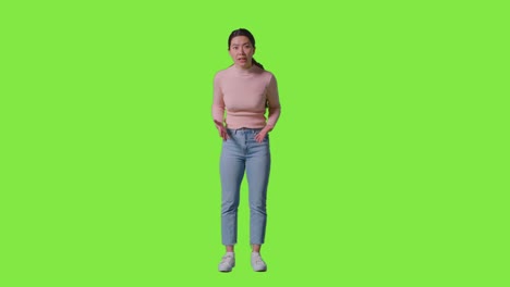 full length studio portrait of frustrated angry woman shouting at camera standing against green screen