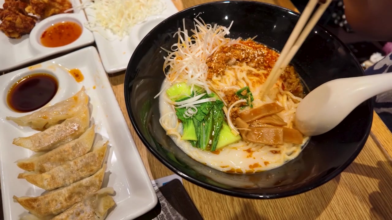 Persona che mangia ramen piccante con bacchette e cucchiaio al ristorante