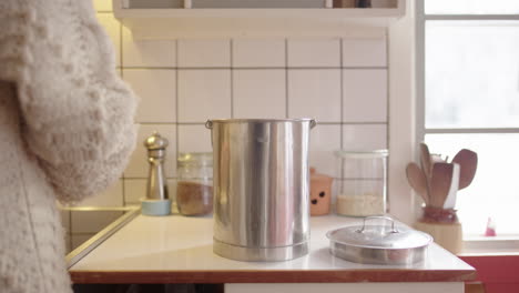 una mujer en la cocina descarta verduras caducadas en un contenedor de acero inoxidable