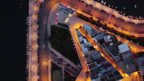 Cinematic topdown  moving drone shot at night at Bari, Italy with cars passing on the road.