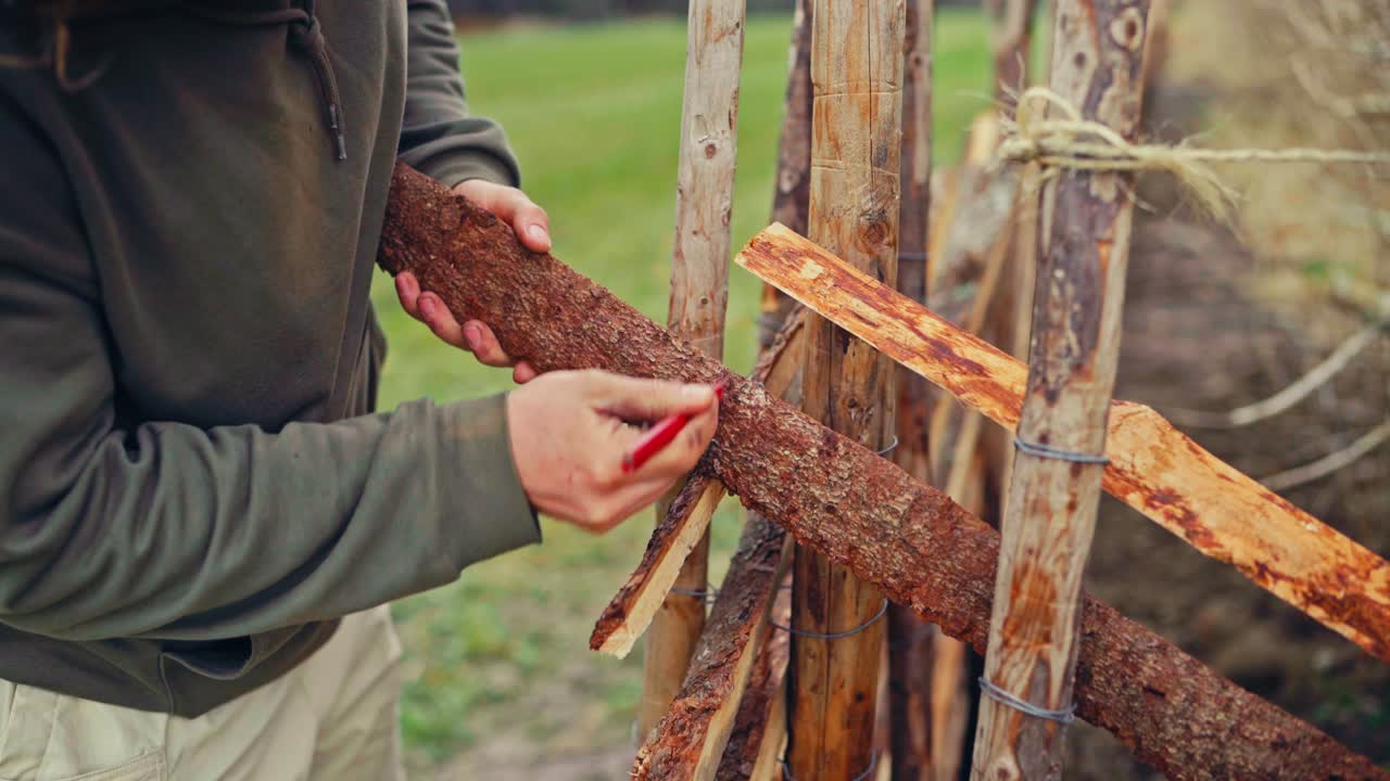 A Man Is Building A Skigard Made Of Split Logs. Close-up Shot