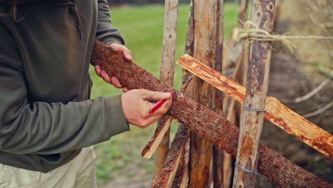 a man is building a skigard made of split logs. close-up shot