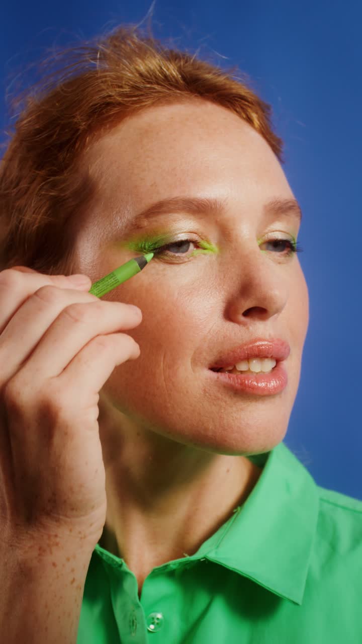 Woman applying green eyeliner