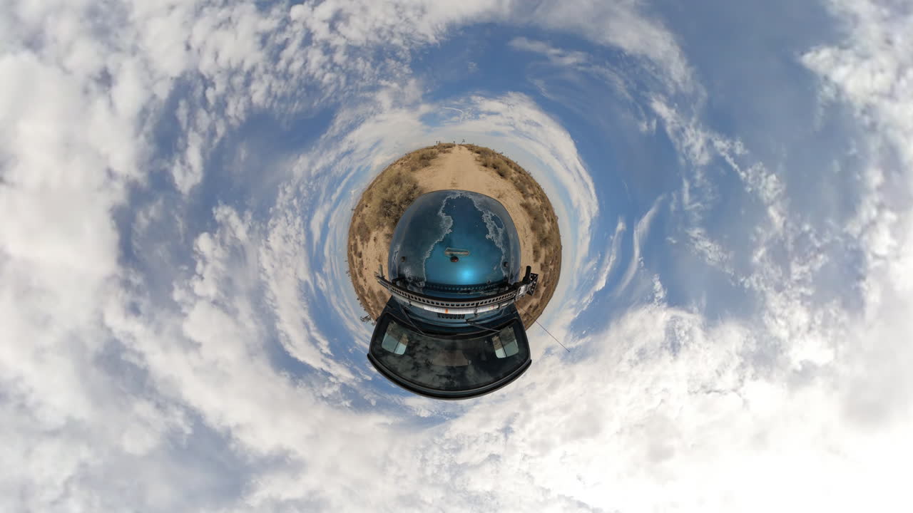 소형 세계에 걸쳐 있는 회전초와 조슈아 트리가 있는 작은 사막 행성 주변을 차량이 주행합니다.