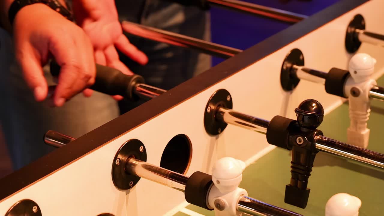 Detailed view of hands maneuvering foosball rods and figures in a dynamic match setting.