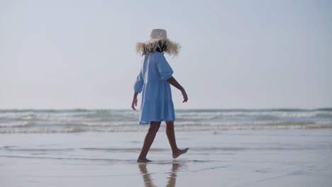 Cute-Girl-In-Straw-Hat-Walking-Along-Seashore-Barefoot