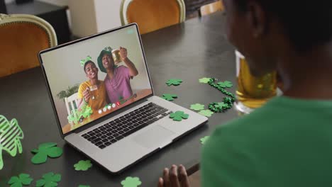 Amigos-Afroamericanos-Sonrientes-Con-Cerveza-Usando-Artículos-En-Forma-De-Trébol-En-Videollamada-En-Una-Computadora-Portátil