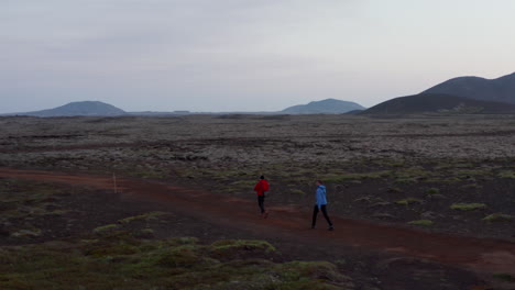Birds-eye-orbit-three-people-hikers-walking-highlands-in-Iceland-exploring.-Aerial-view-three-explorer-walking-pathway-excursion-exploring-extreme-icelandic-landscape