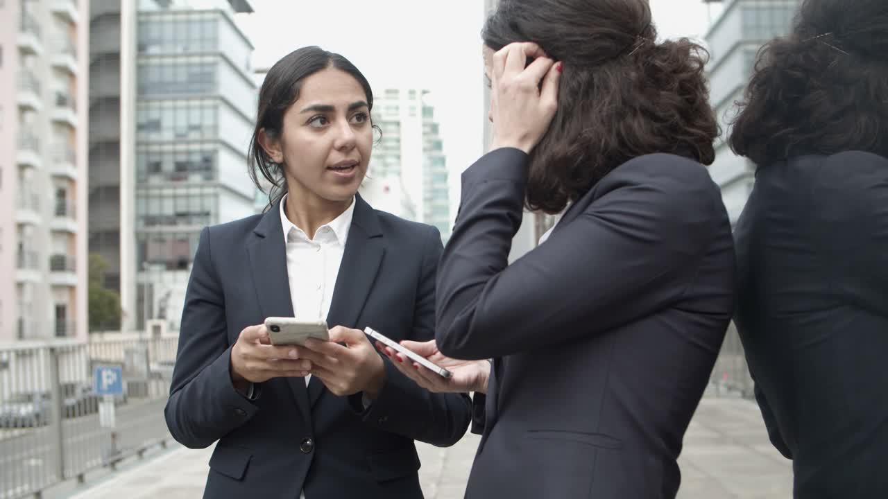 Donne d'affari che parlano e usano smartphone per strada