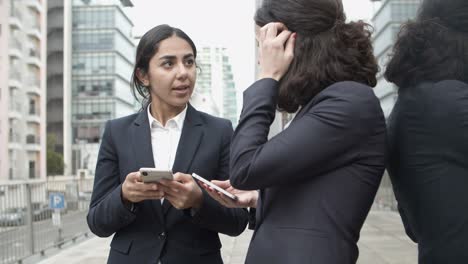 businesswomen talking and using smartphones on street