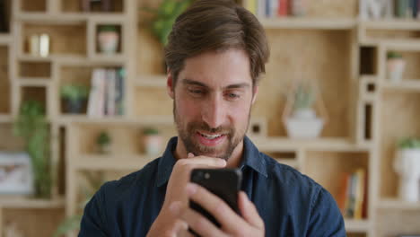 portrait of handsome young man using smartphone texting browsing enjoying mobile communication on cellphone technology in modern home background