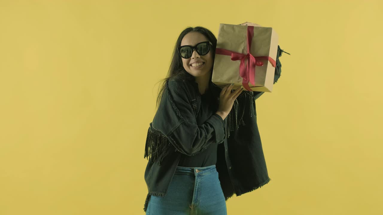 chica feliz con una caja de regalos sobre un fondo amarillo