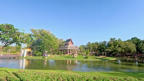 a tranquil pavilion by a pond in rama ix park, bangkok, captured under clear blue skies with lush greenery