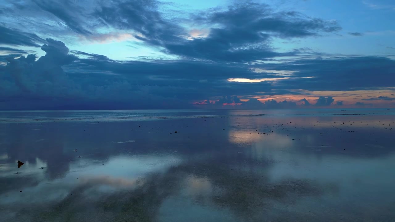 Calm ocean water reflecting a dramatic cloudy sky during a peaceful sunset creating a serene atmospheric landscape. Nice aerial view fly reverse drone panorama speed ramp hyper motion time lapse