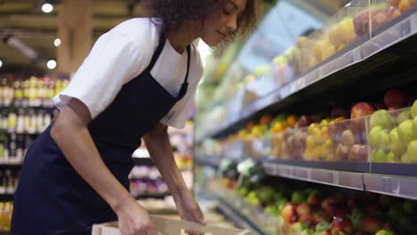 Bastante-Trabajador-Multirracial-En-Delantal-Negro-Almacenando-Las-Frutas-En-El-Supermercado