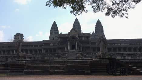 panorámica exterior ancha a la derecha de las tres torres del antiguo templo de angkor wat desde el exterior de una entrada con los naga a ambos lados de las escaleras en primer plano