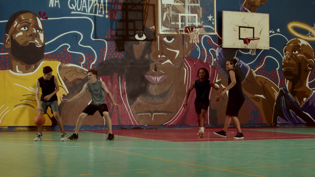 Young men playing basketball on a vibrant indoor court with graffiti murals