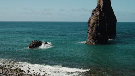 volcanic rock formations off the shore with waves splashing