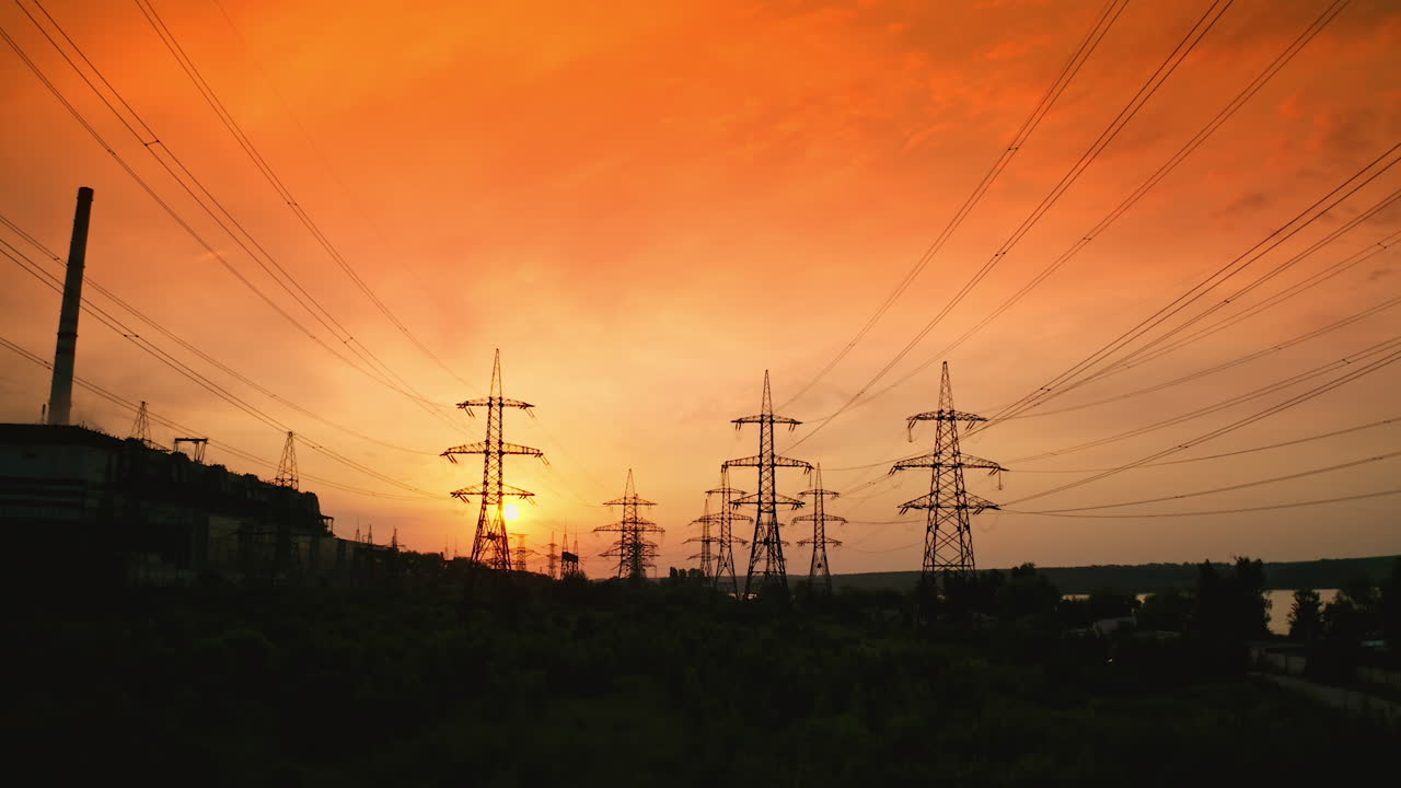 Electricity pylons at sunset. Transmission towers. Silhouette of high-voltage electic towers that transport electric power from generating stations to electrical substations. Aerial view.