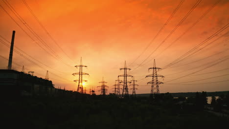 electricity pylons at sunset. transmission towers. silhouette of high-voltage electic towers that transport electric power from generating stations to electrical substations. aerial view.