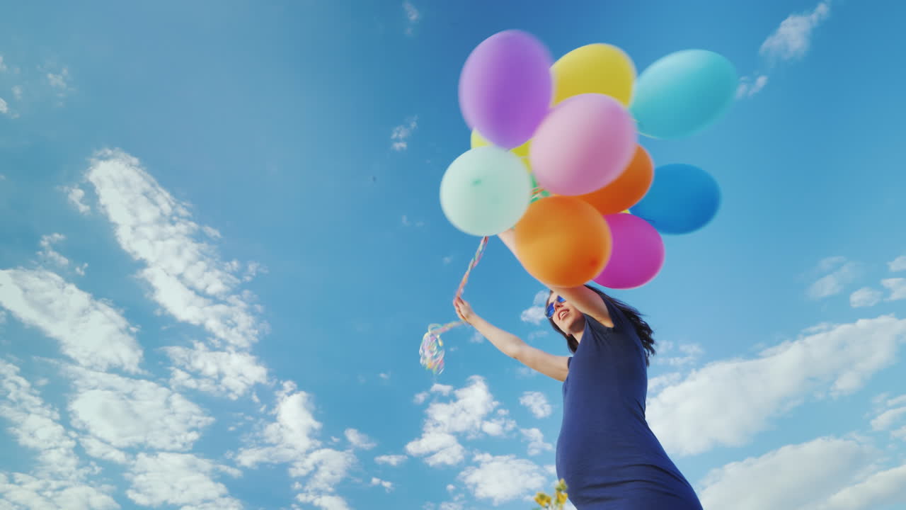 푸른 하늘을 배경으로 풍선을 가지고 노는 행복한 임산부