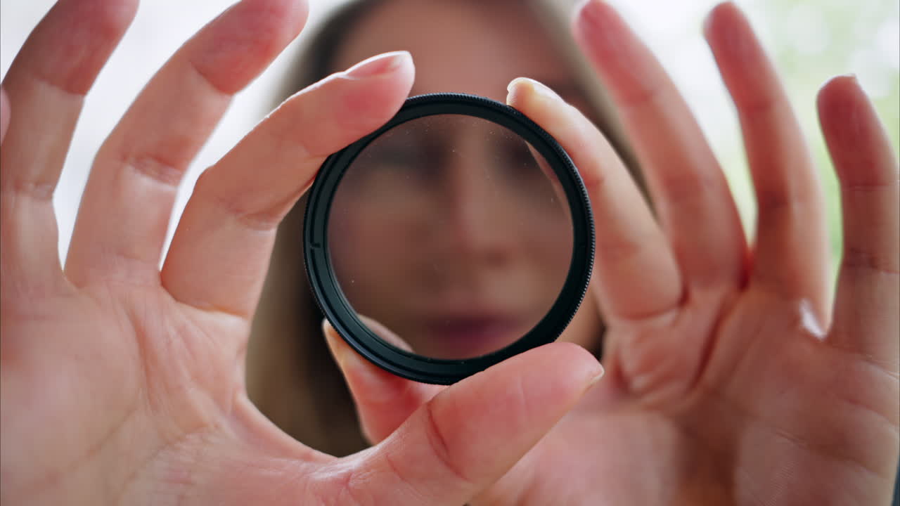 Woman looking through camera lens neutral density nd filter while rotating it