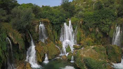 aerial pulls back from kravice waterfall in dense green bosnian forest