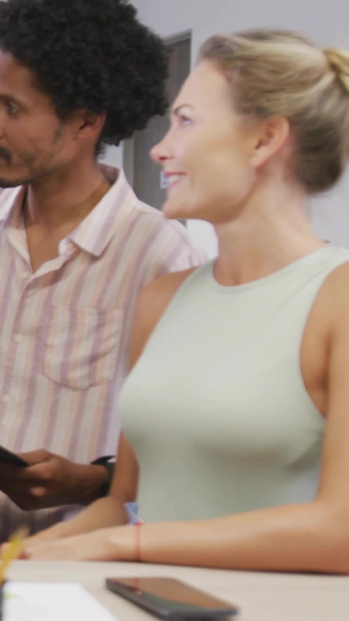 Vertical video: Man tapping phone while woman smiling, social tags popping over frame for ad