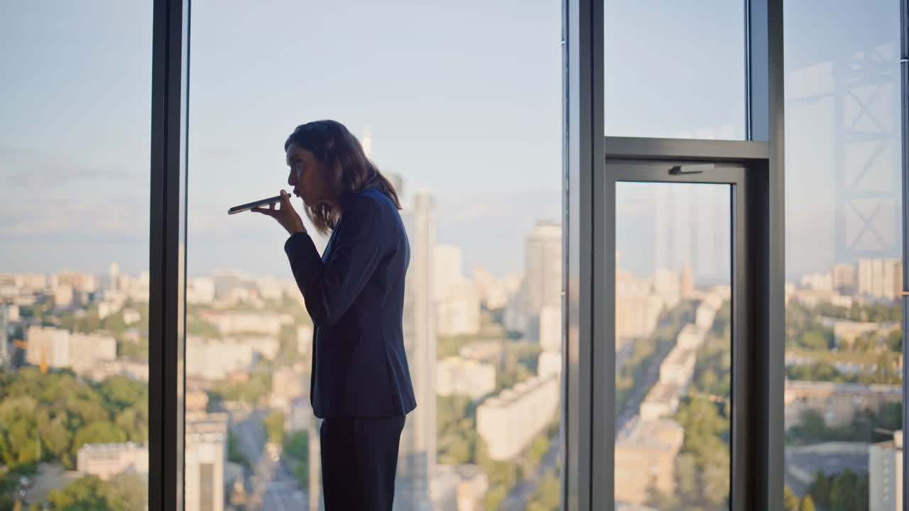 Lady boss quarrelling cellphone by panoramic window inside highrise building