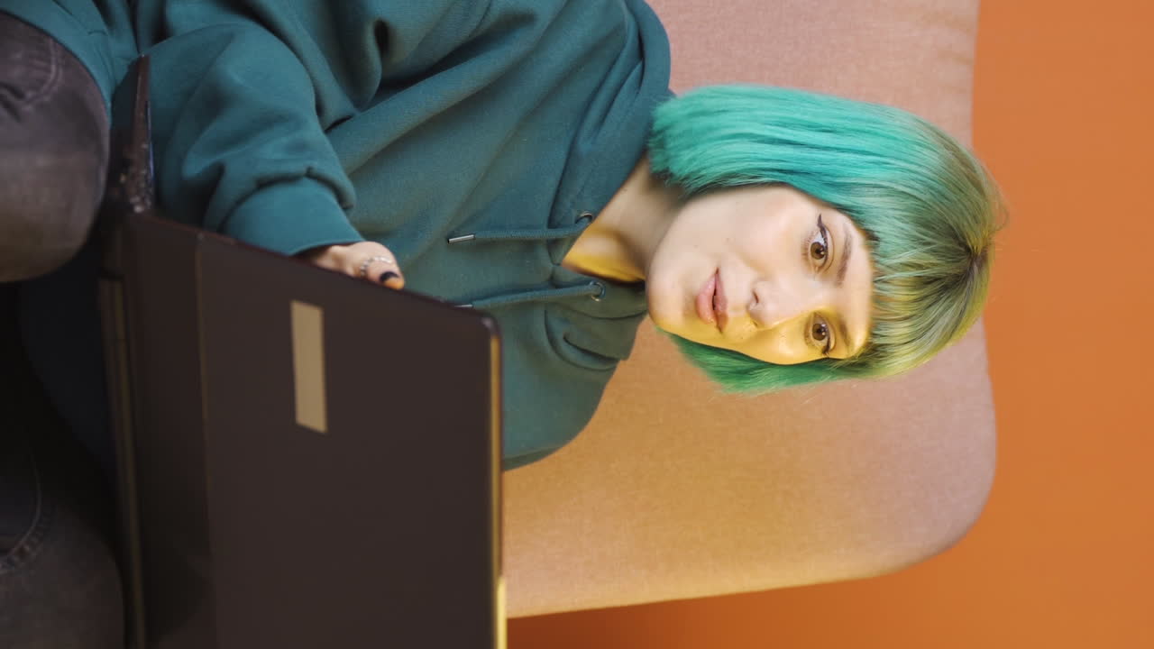 video vertical de una mujer joven mira la computadora portátil y se alegra.