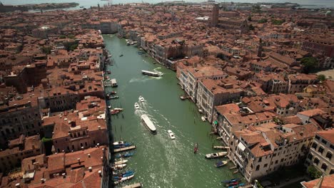 aerial drone fly above boats sailing in grand canal of venice, italy in summer warm weather, gondolas and city architecture in romantic travel european destination