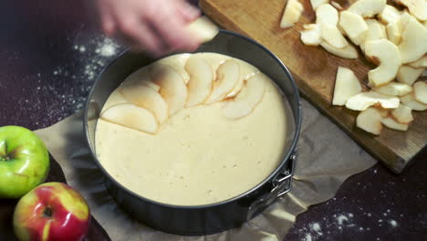 chef puts apple pieces in baking pan. baking apple pie. man making dessert