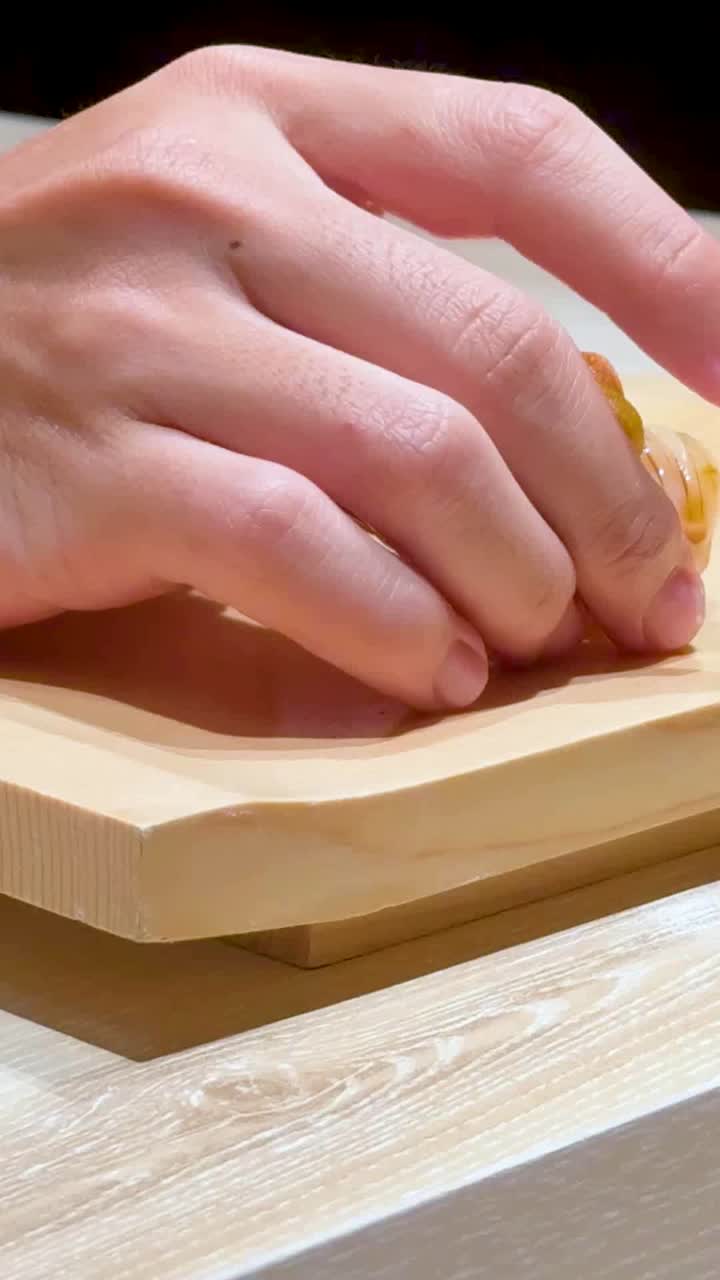 요리사는 나무판에 수시를 놓습니다.