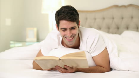 Hombre-Guapo-Sonriente-Leyendo-En-La-Cama