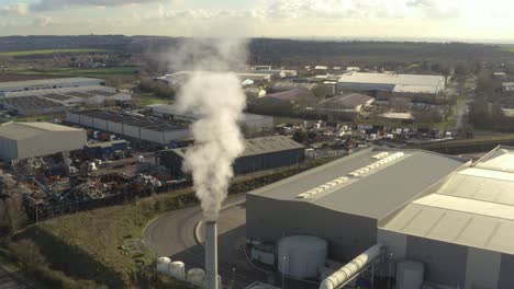 Aerial-drone-coming-down-across-smoking-chimney-and-factory