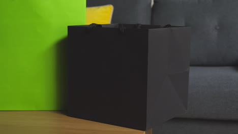 primer plano de un hombre poniendo regalos envueltos en bolsas con etiqueta en la mesa en el salón en casa