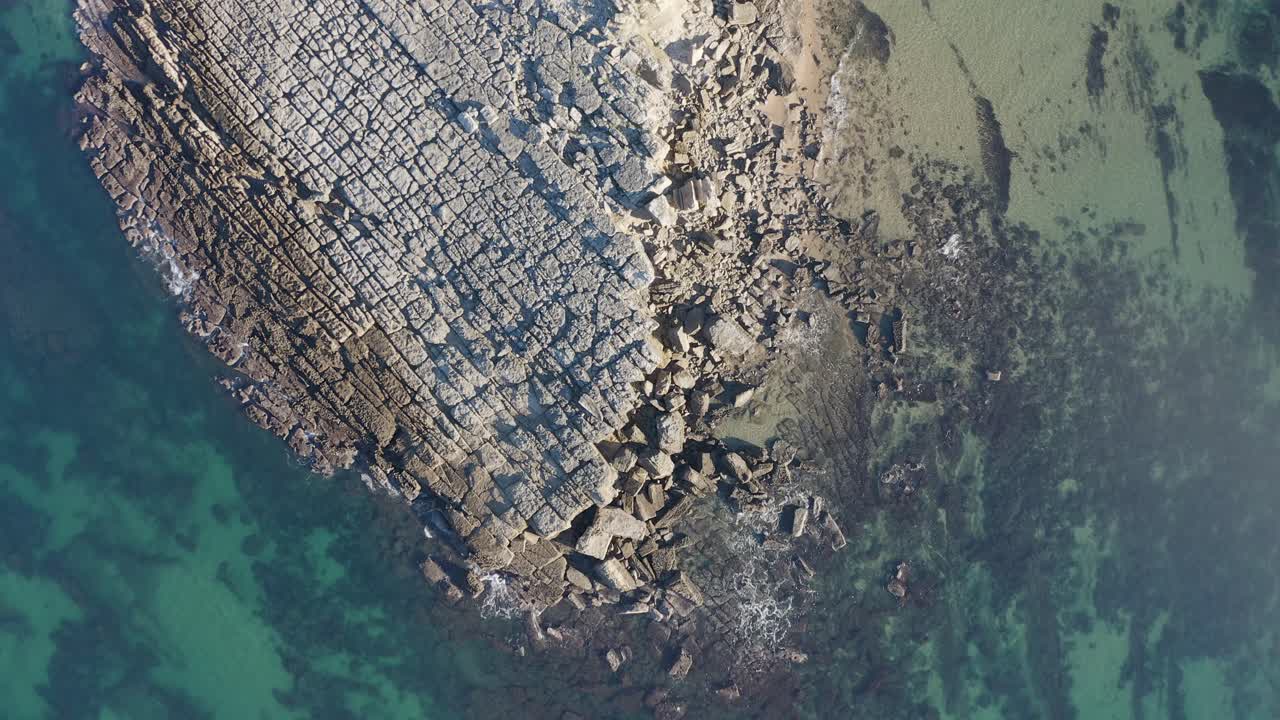Aerial top down view of rocky bay and crystal blue waters along Lisbon's sunny coastline