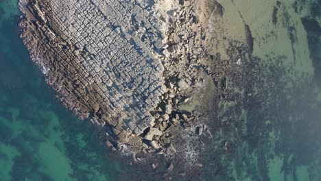 Aerial-top-down-view-of-rocky-bay-and-crystal-blue-waters-along-Lisbon's-sunny-coastline