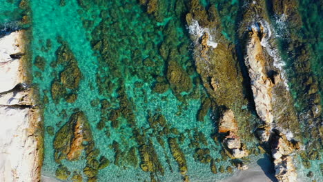 Vista-Aérea-De-Arriba-Hacia-Abajo-Moviéndose-Lentamente-Hacia-La-Derecha,-Aguas-Cristalinas-Del-Mar-Mediterráneo-Y-Hermosas-Rocas-Largas