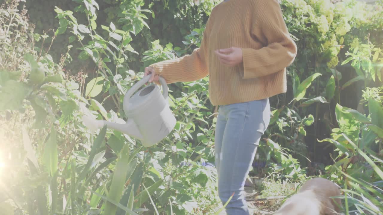 정원에서 식물에 물을 공급하는 백인 여성에 대한 빛의 반점