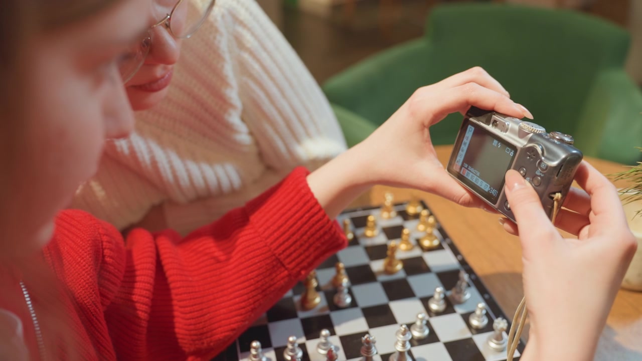 Giovane donna che rivede le foto di una partita a scacchi su una fotocamera digitale
