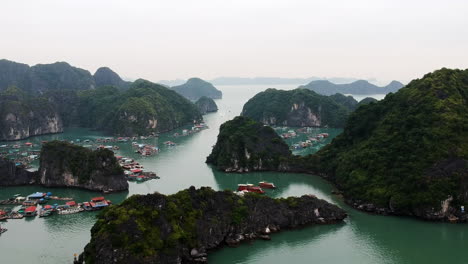 Halong-Bucht,-Vietnam,-Fischerboote-Und-Fischerdorf-Drohnenvideo-über-Dem-Meer-Und-Dem-Berg-Mit-Grünen-Kalksteinsäulen