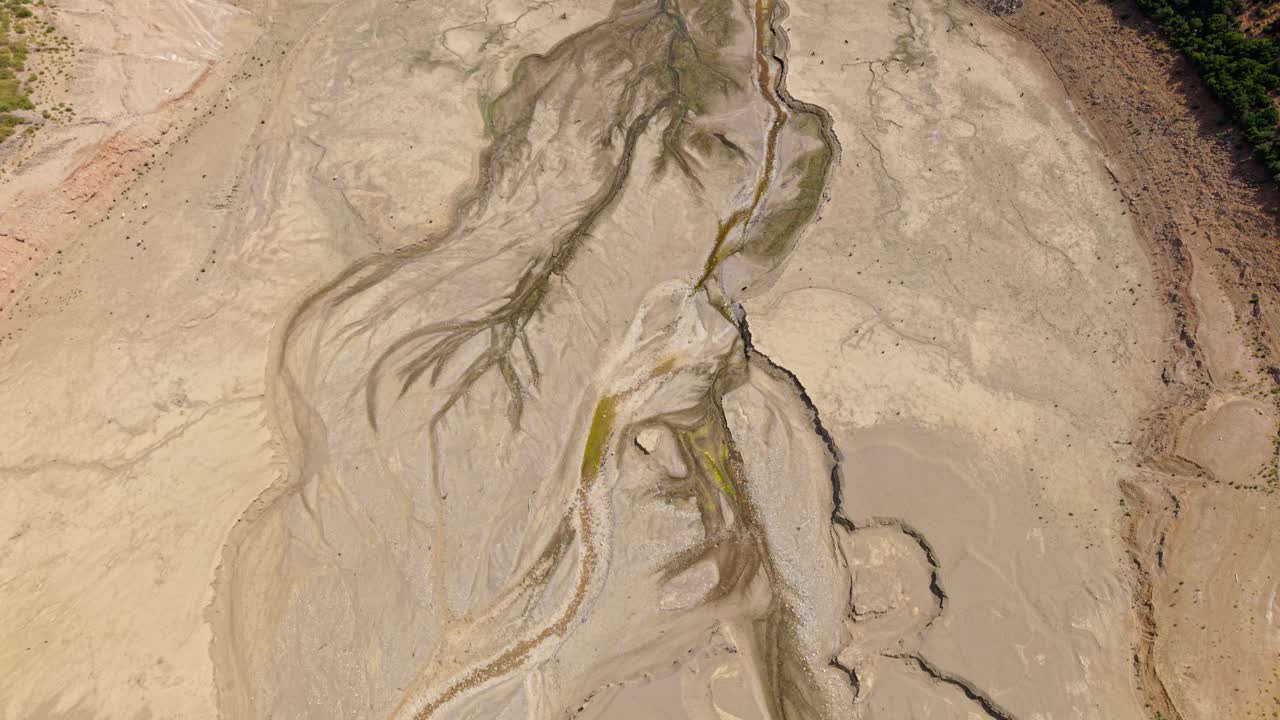 Aerial establishing of cracked earth and dried lakebed forming winding patterns in barren Greek terrain