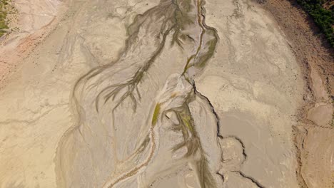 aerial establishing of cracked earth and dried lakebed forming winding patterns in barren greek terrain