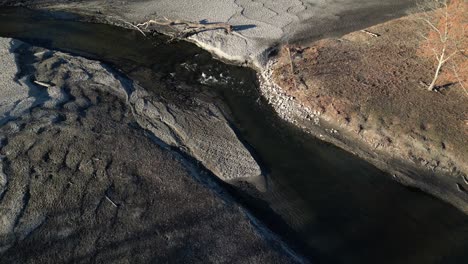 Drohnenaufnahme-Eines-Teichflusses,-Der-Durch-Einen-Umgestürzten-Baum-Stark-Erodiert-Ist