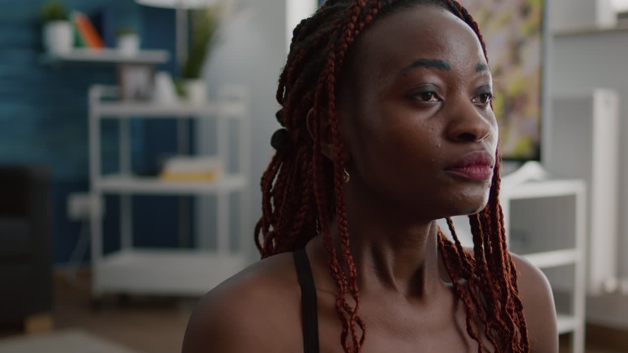 눈을 감고 요가 지도에 로터스 포즈로 앉아 있는 적합한 흑인 여성