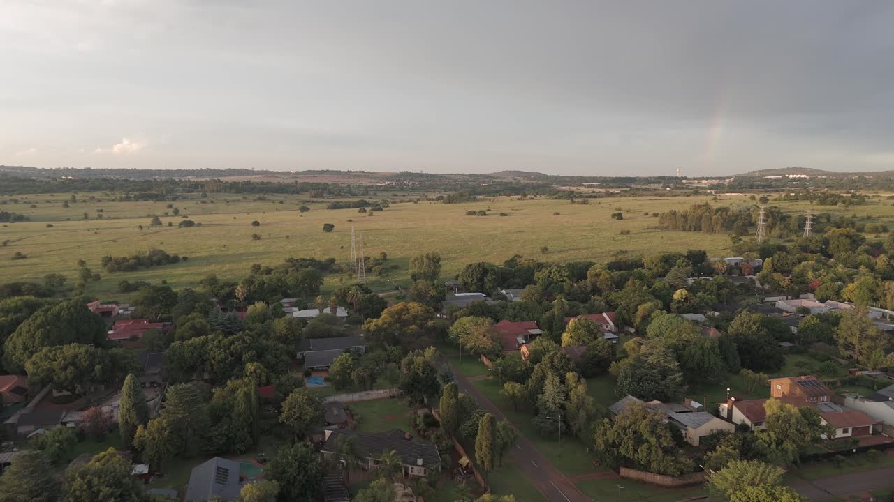 4k 항공, 주거 주택의 도시 풍경 위를 날아, 하늘에 무지개의 암시와 함께 개방된 필드를 향해 이동, 센추리온, 남아프리카