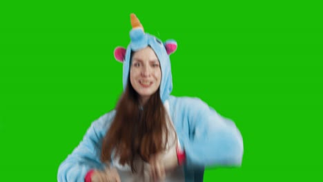 portrait of a cute young brunette girl in a beautiful unicorn costume on chrome key green background. smiling and playing. animator in costume. unicorn pajamas. 4k video with alpha channel